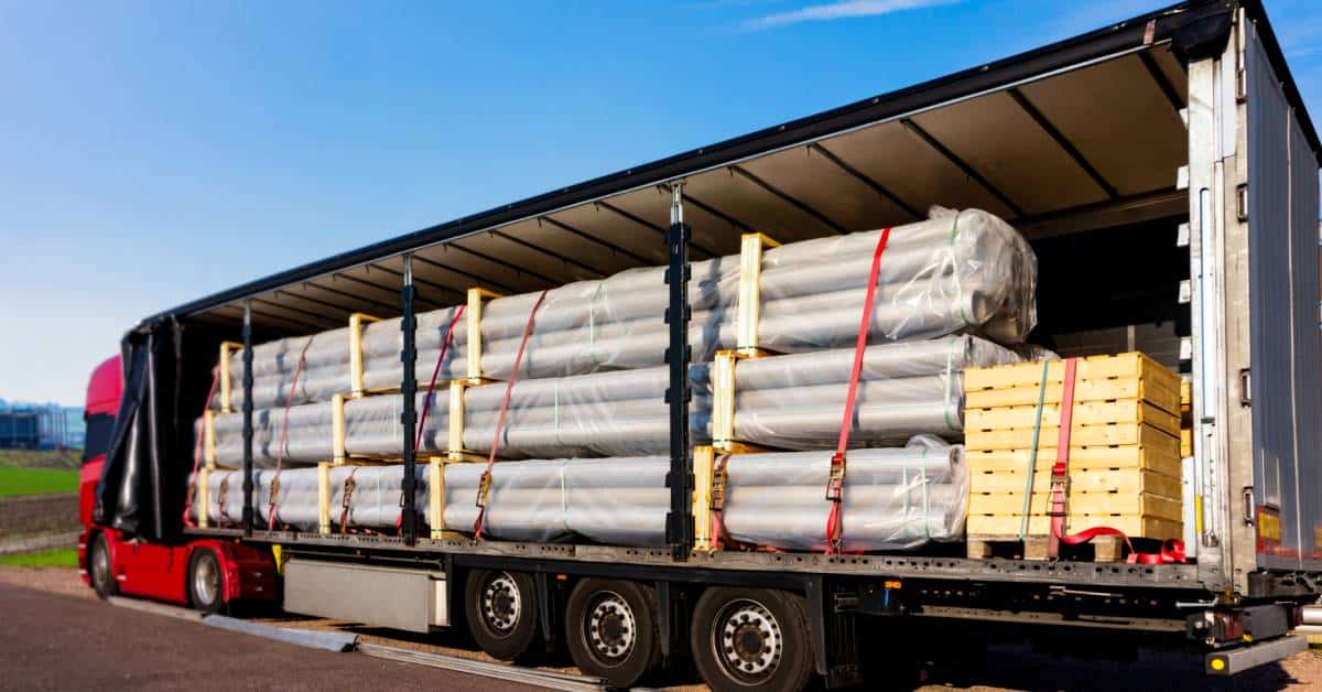 A large semi truck trailer showing the interior which is loaded with cargo. All of the cargo is securely strapped in place.
