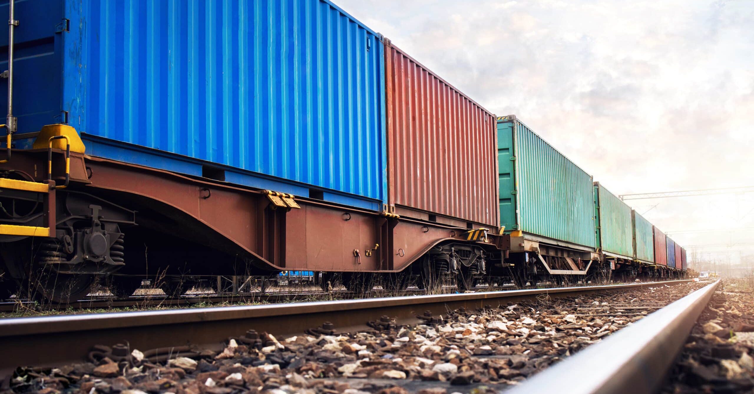 An aerial view of a large cargo ship carrying hundreds of multicolored shipping containers across the ocean.
