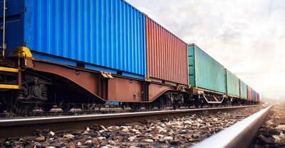 An aerial view of a large cargo ship carrying hundreds of multicolored shipping containers across the ocean.